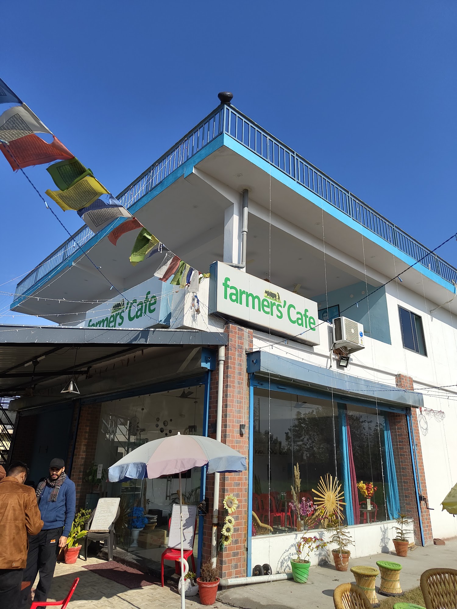 Farmers' Cafe exterior with prayer flags against a mountain sky
